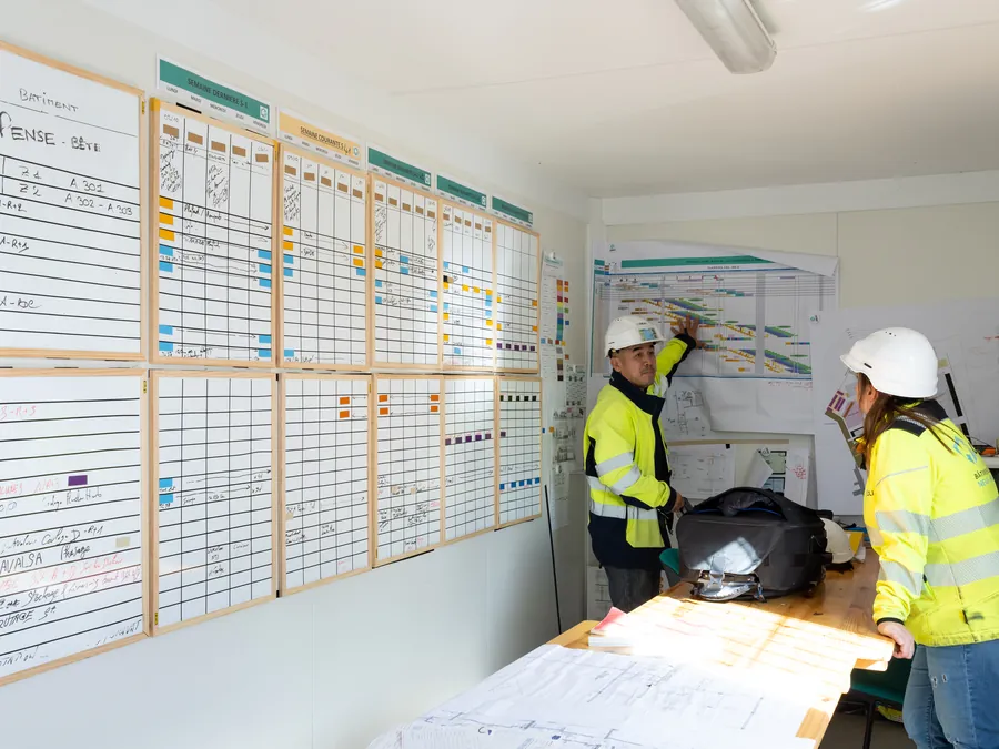 Deux collaborateurs CREALI échangent devant le planning de chantier